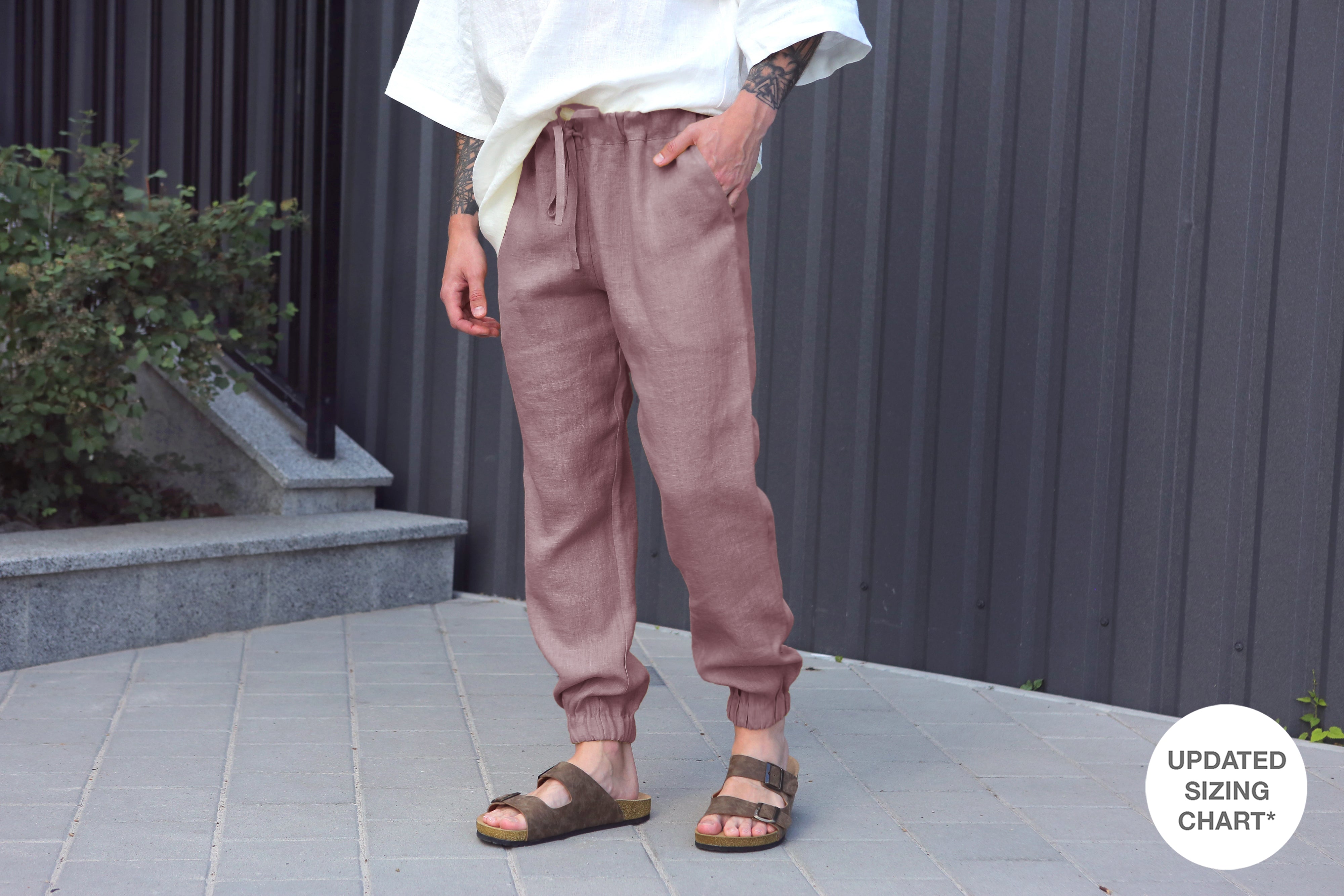 Person wearing latte jogger pants and sandals standing on a tiled floor with a plant in the background.