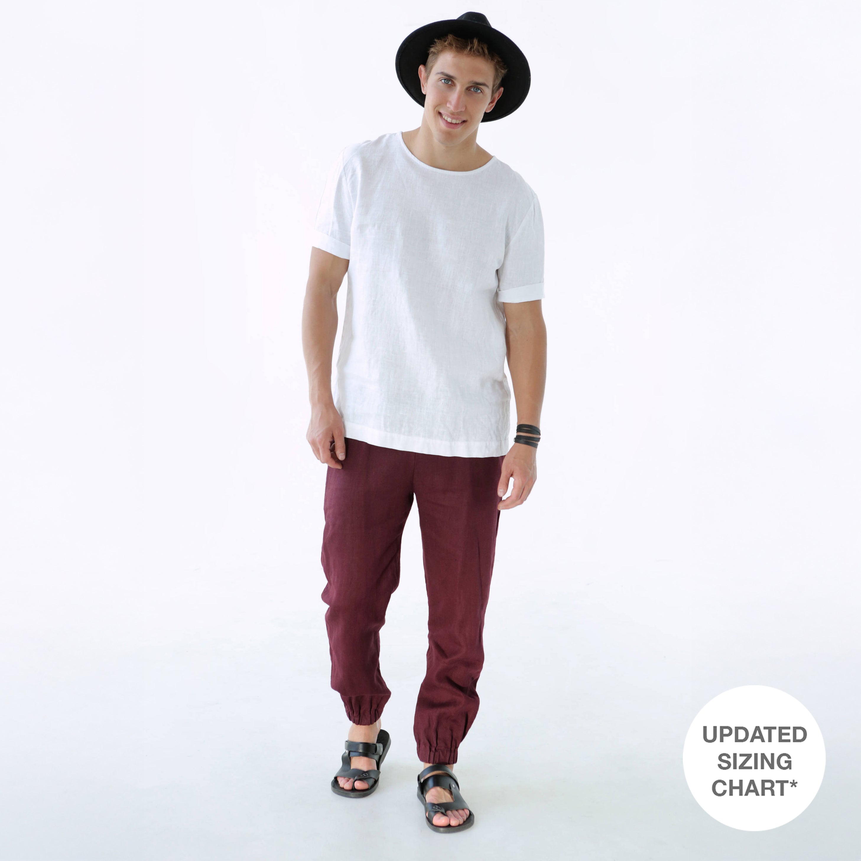 Person wearing a white t-shirt, burgundy pants, and a black hat on a white background