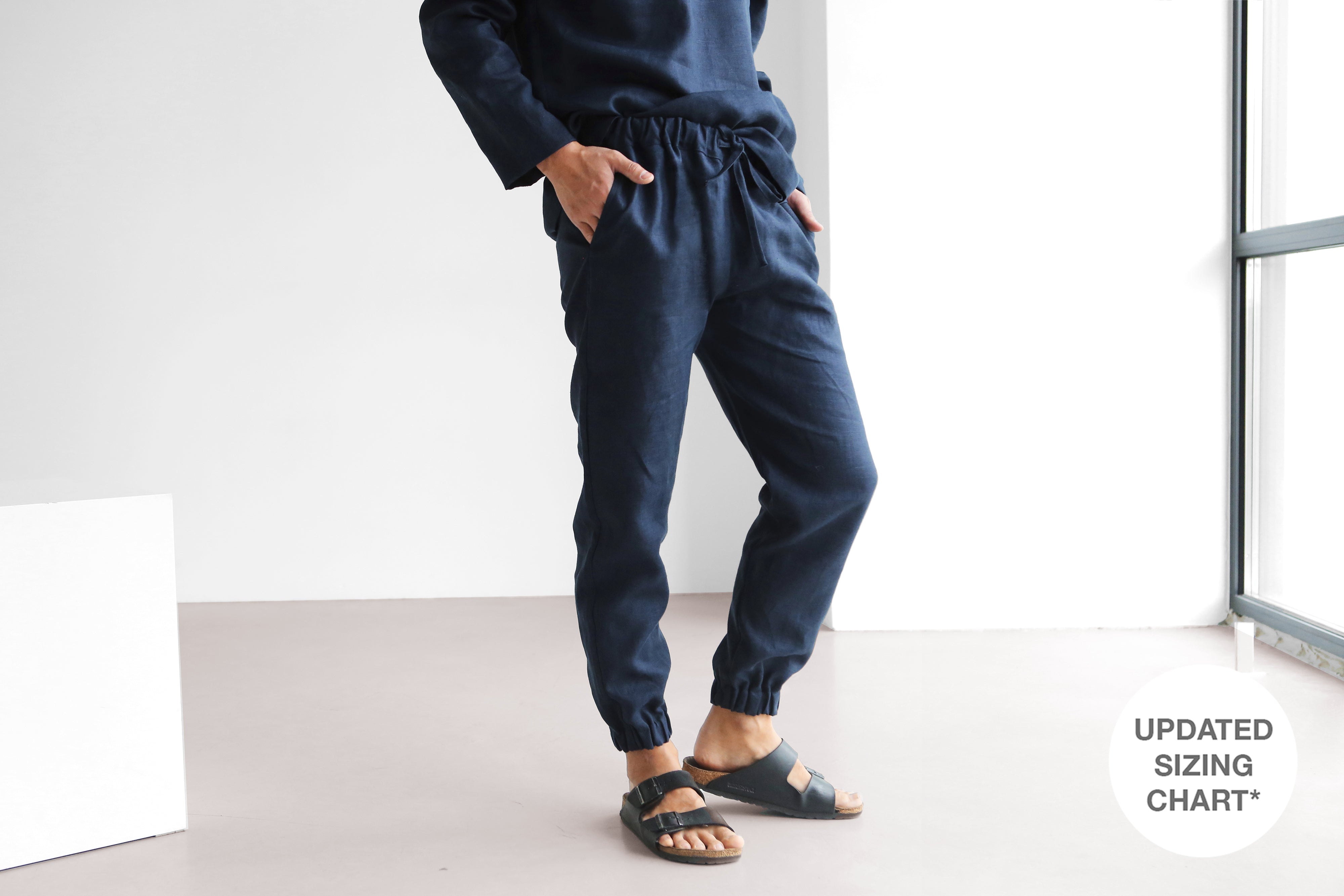 Person wearing navy blue jogger pants standing in a minimalistic room.