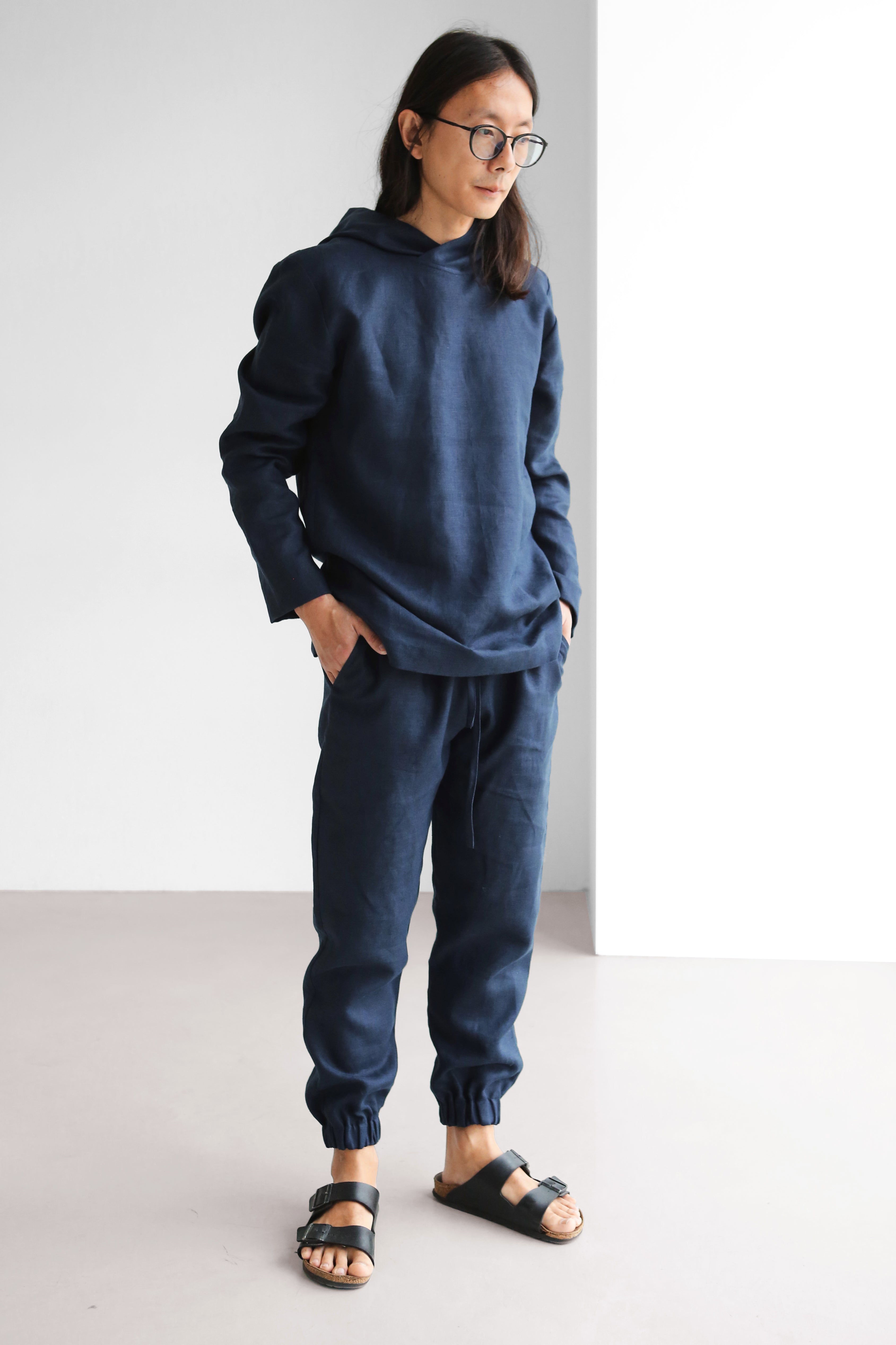 Person wearing a blue hoodie and jogger pants standing against a white background