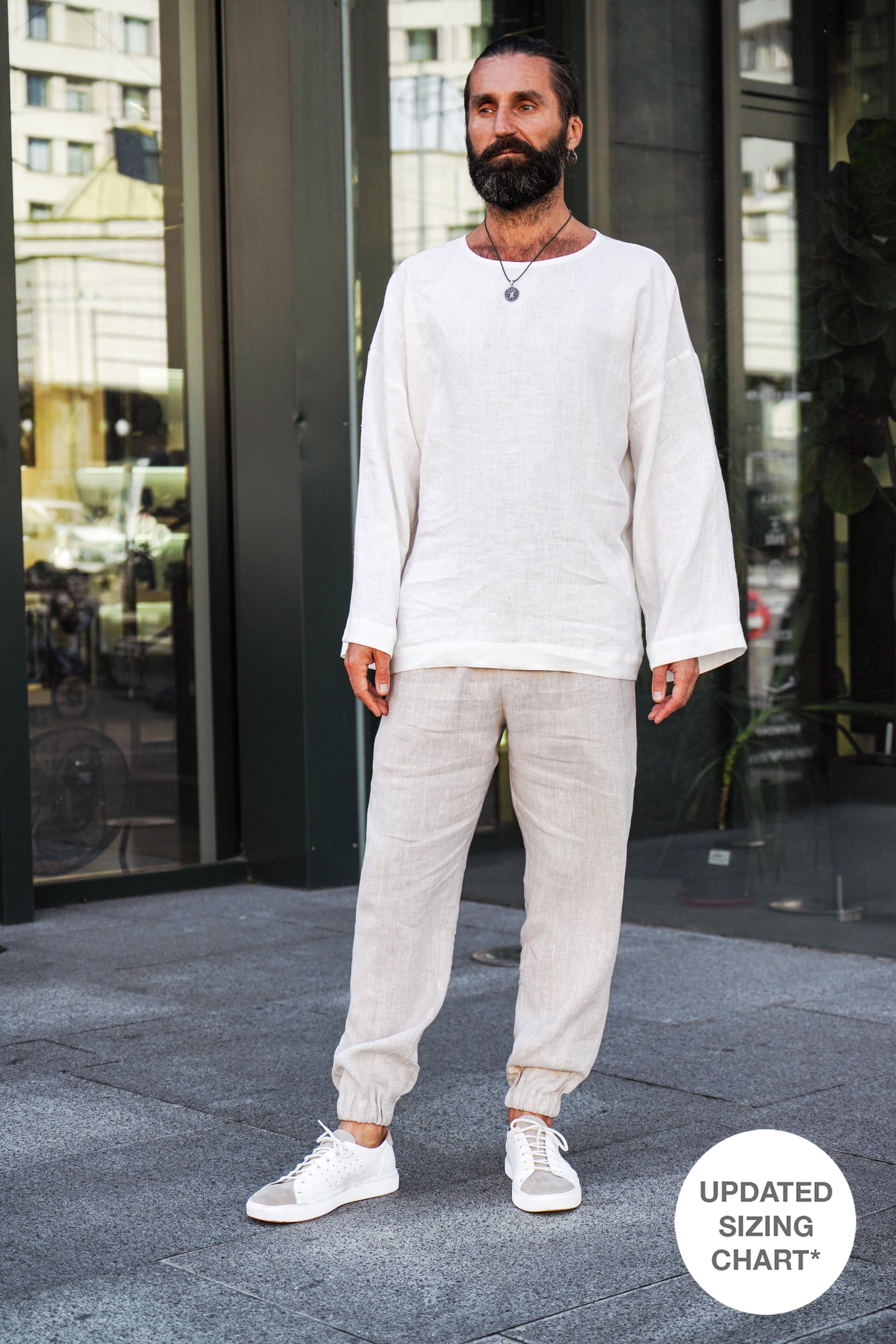 A man wearing a white long-sleeve shirt and beige joggers standing on a city street