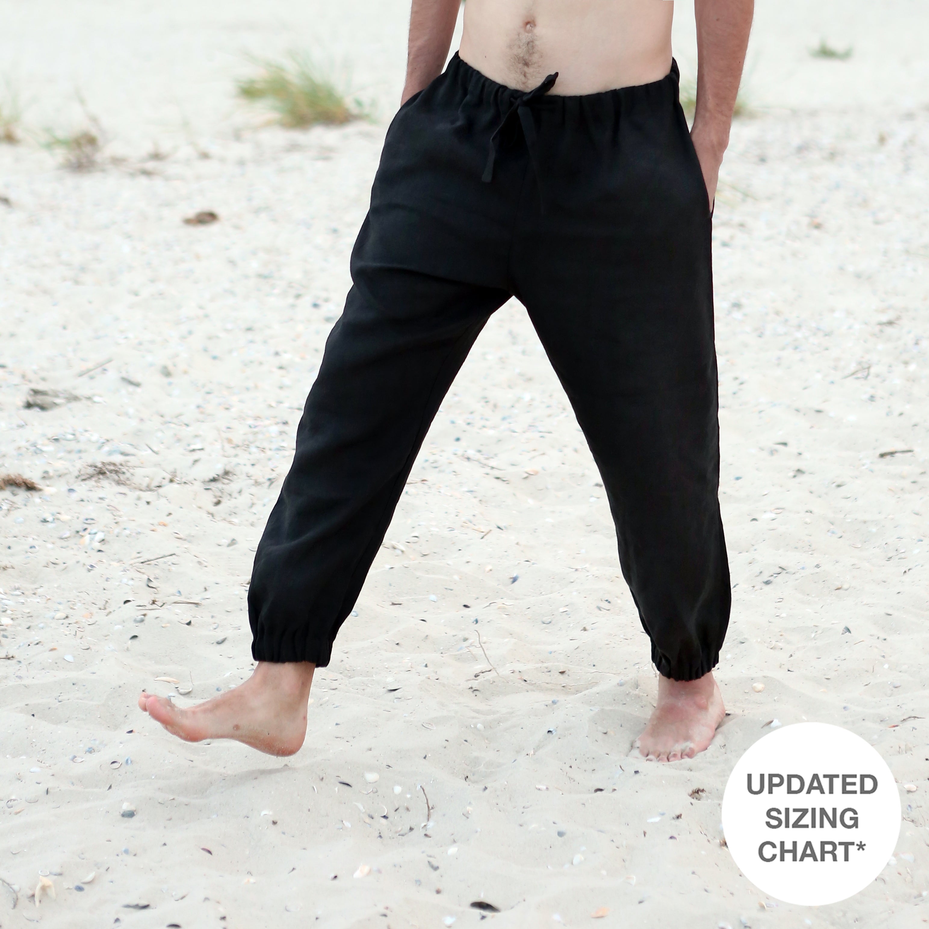 Person wearing black pants standing on a sandy beach.