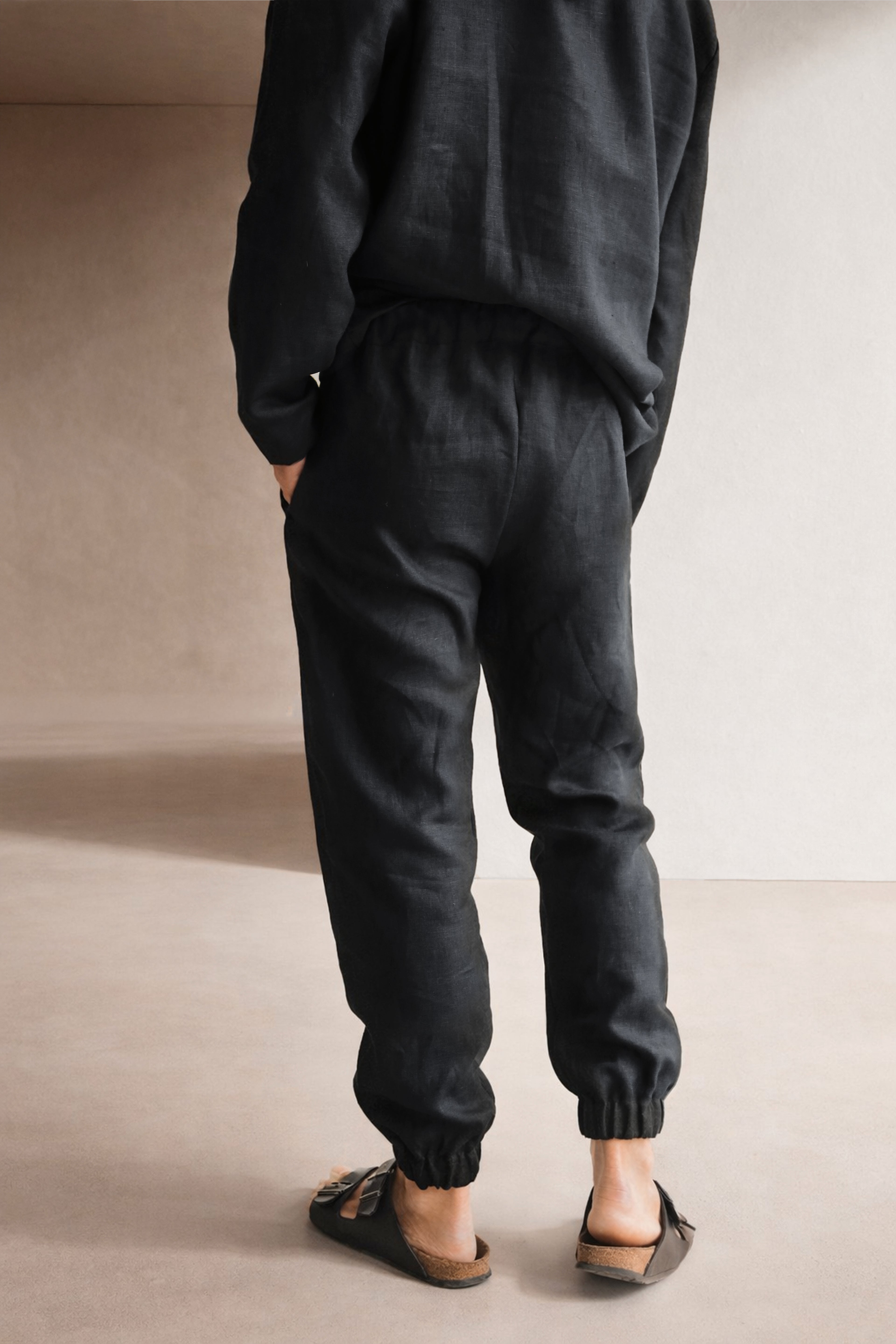 Person wearing black pants and a dark t-shirt against a neutral background